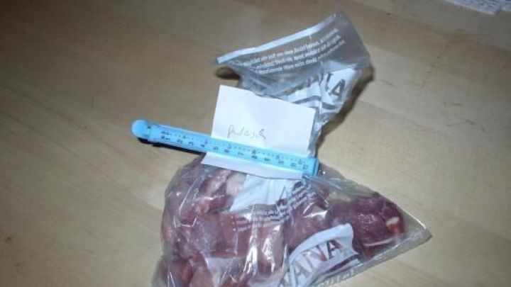 Ein gefrorenes Lebensmittel in einer durchsichtigen T&uuml;te mit einem Etikett zum Beschriften liegt auf einem Holzstuhl.