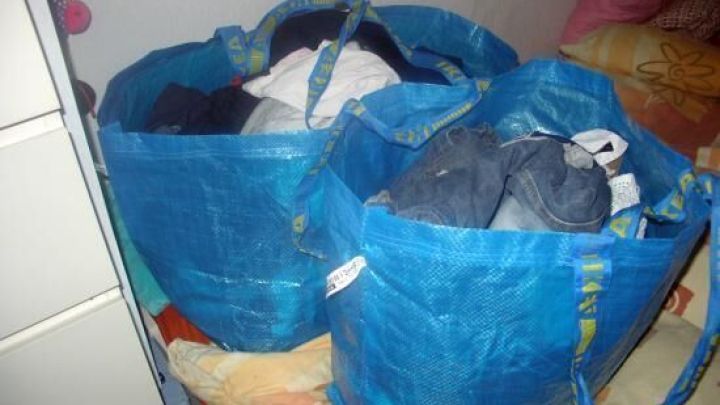 Zwei gro&szlig;e blaue Taschen sind mit W&auml;sche gef&uuml;llt und stehen auf einem Bett, um die W&auml;schekorb-Alternative zu zeigen.