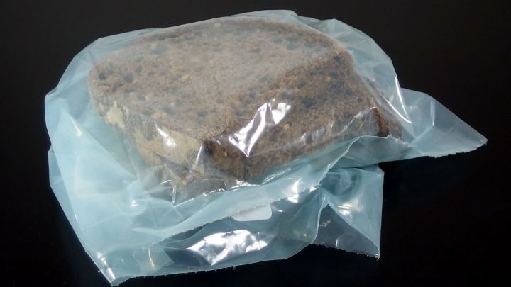 Altes Brot ist in einer durchsichtigen Plastikt&uuml;te verpackt und liegt auf einem schwarzen Untergrund, bereit zur Verwendung.