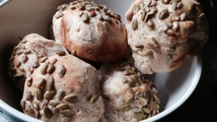 Br&ouml;tchen mit K&uuml;rbiskernen liegen in einer Schale auf einem Tisch. Sie sind frisch gebacken und haben eine goldene Kruste.