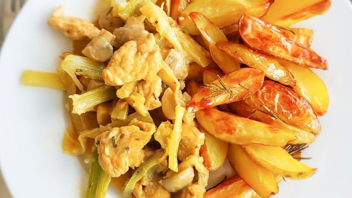 Gebackene Zitronenkartoffeln liegen gebr&auml;unt und knusprig neben einer Portion zartem H&auml;hnchen mit Gem&uuml;se auf einem Teller.