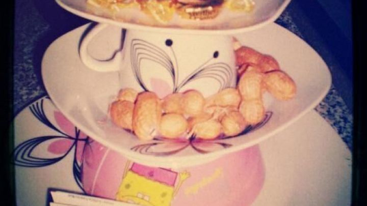 Eine Etagere zeigt auf mehreren Ebenen S&uuml;&szlig;igkeiten und Snacks in einer dekorativen Pr&auml;sentation auf einem Tisch.