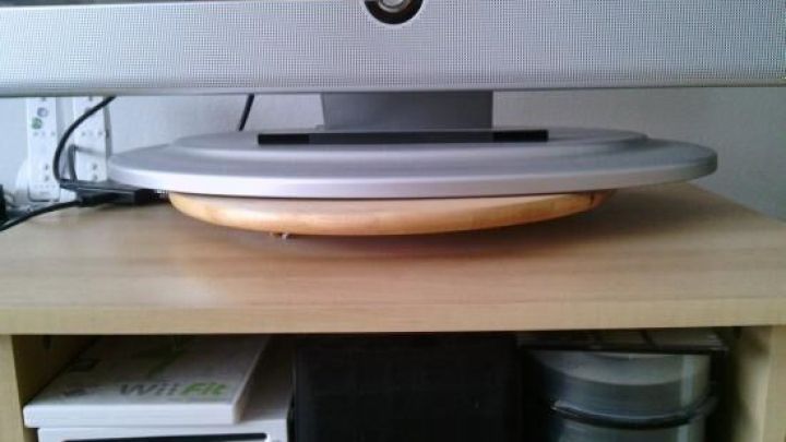 Ein Drehteller f&uuml;r den Fernseher steht auf einem Holzregal, dreht sich und erm&ouml;glicht so verschiedene Blickwinkel auf den Bildschirm.