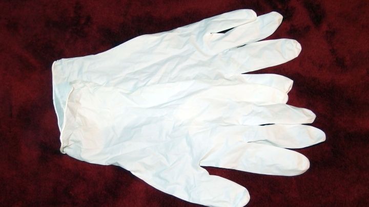 Ein paar wei&szlig;e Gummihandschuhe liegen auf einem roten Tuch, bereit zur Verwendung bei der Stuhlgang Inkontinenzbehandlung.