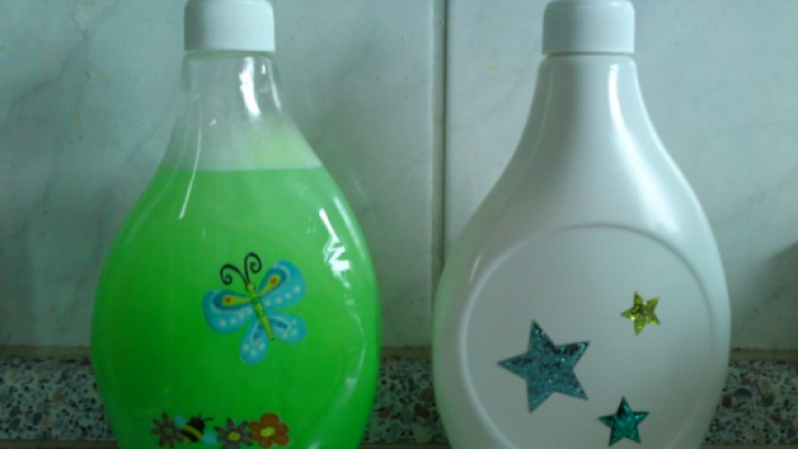 Zwei dekorativ aufgeh&uuml;bschte Sp&uuml;lmittelflaschen stehen auf einer K&uuml;chentheke, eine gr&uuml;ne mit Schmetterling, die andere wei&szlig; mit Sternen.