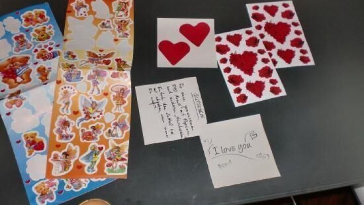 Bunte Aufkleber und Karten mit Herzmotiven liegen auf einem Tisch, bereit f&uuml;r eine nette, kosteng&uuml;nstige Valentinstags&uuml;berraschung.