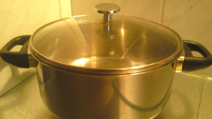 Ein Glastopf mit metallischem Deckel steht auf einer Arbeitsplatte in einer K&uuml;che, bereit zum Kochen oder Aufbewahren.