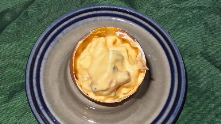 Ein Eiersalat befindet sich in einer Eierschale auf einem Teller, umgeben von einem gr&uuml;nen Tuch.