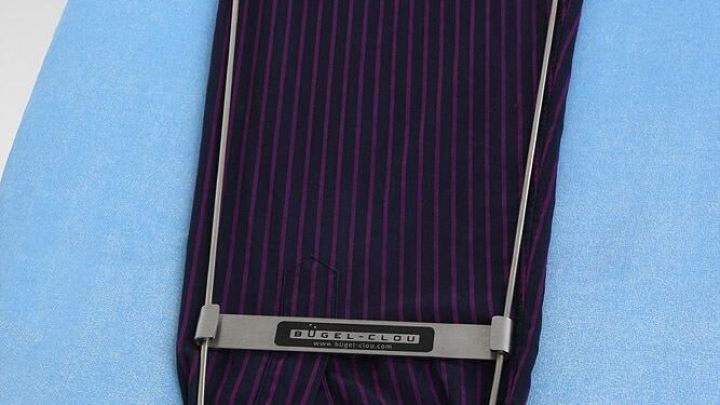 Ein Hemds&auml;rmel liegt flach auf einem blauen B&uuml;geltuch, w&auml;hrend eine B&uuml;gelhilfe den &Auml;rmel f&uuml;r das B&uuml;geln fixiert.