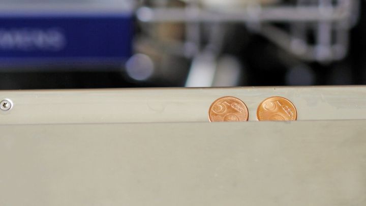 Zwei 5-Cent-M&uuml;nzen liegen auf der obersten Kante einer Sp&uuml;lmaschine, die in einer modernen K&uuml;che steht.