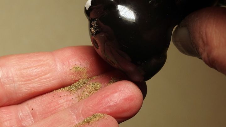 Ein Hand h&auml;lt ein schwarzes Objekt, das kleinen Sand auf die offene Hand verteilt, ideal f&uuml;r Tipps gegen kalte F&uuml;&szlig;e.