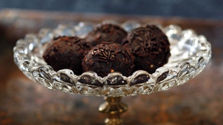 Schokoladige Rumkugeln liegen auf einem eleganten Glasst&auml;nder in einer stilvollen K&uuml;che.