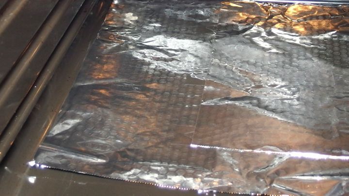 Ein Backofen ist mit Alufolie ausgelegt, die gl&auml;nzend auf dem Rost liegt, um ihn sauber zu halten.