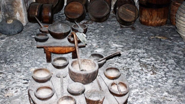 Holzgeschirr und T&ouml;pfe stehen auf einem Tisch in einer rustikalen Umgebung, die traditionelles Kochen simuliert.
