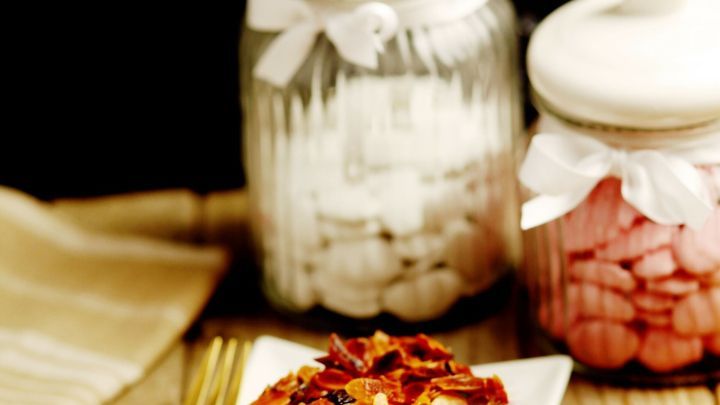 Ein St&uuml;ck Kuchen steht auf einem wei&szlig;en Teller und wird von zwei Glasbeh&auml;ltern mit Lagerwaren umgeben.