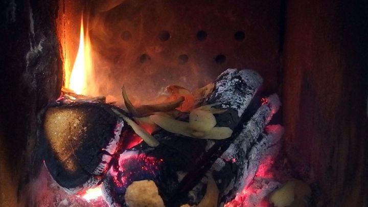 Ein Kamin brennt mit gl&uuml;henden Kohlen und Holzscheiten, umgeben von den Mauern des Schornsteins.