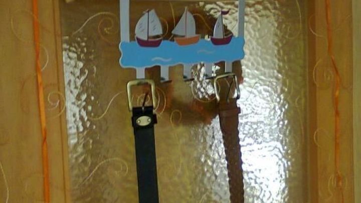 Ein G&uuml;rtelhalter h&auml;ngt an einer T&uuml;r und h&auml;lt zwei G&uuml;rtel ordentlich aufbewahrt, um Platz zu sparen.