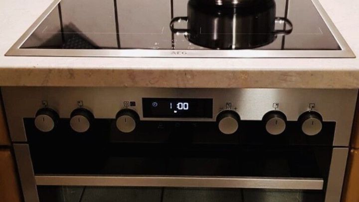 Ein Edelstahltopf steht auf einem Induktionskocher in einer modernen K&uuml;che, umgeben von wei&szlig;en Fliesen.