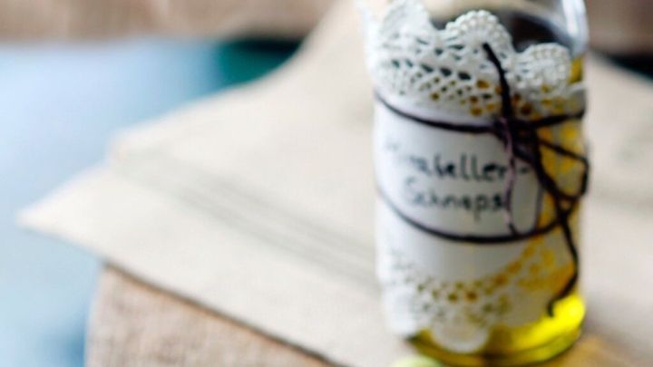 Eine Flasche Mirabellenschnaps steht auf einem Holzbrett, umgeben von frischen Mirabellen und gr&uuml;nen Bl&auml;ttern.