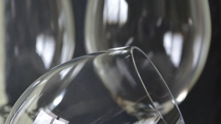 Klaren Weingl&auml;ser stehen in einer eleganten Anordnung, w&auml;hrend eines kippt, um eine schlierenfreie Reinigung zu zeigen.