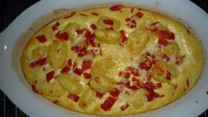 Ein Auflauf mit Gnocchi und roten Paprikast&uuml;cken wird goldbraun gebacken und befindet sich in einer wei&szlig;en Auflaufform.