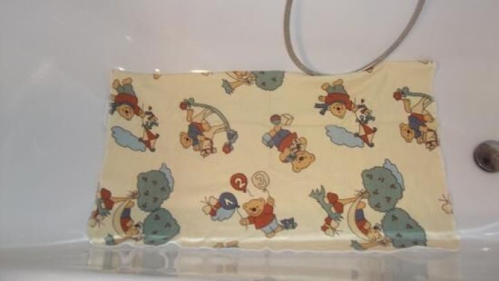 Eine rutschfeste Badewannenmatte mit bunten Mustern liegt in einer Badewanne und verhindert Rutschen beim Baden.