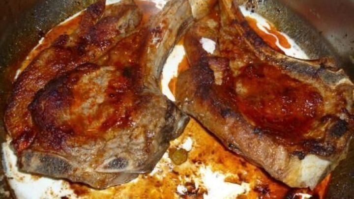 Zwei saftige Kalbskotelettes braten in einer Pfanne, umgeben von einer leicht angebrannten Sauce.