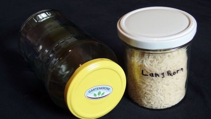 Ein Glasbeh&auml;lter und ein Glas mit Reis stehen auf einem schwarzen Untergrund, passend f&uuml;r die &uuml;bersichtliche Lagerung von Nudeln und Reis.