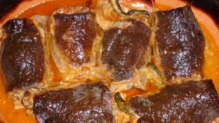 Saftige Rouladen liegen in einer br&auml;unlichen Sauce im R&ouml;mertopf, bereit zum Servieren in einem warmen, rustikalen Umfeld.