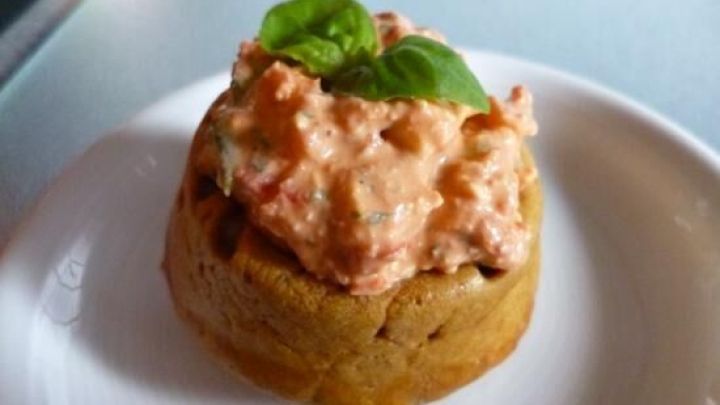 Herzhafter Cupcake mit cremigem Belag und Basilikum, serviert auf einem wei&szlig;en Teller.