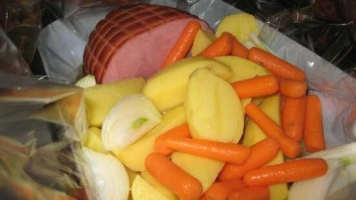Ein Bratschlauch enth&auml;lt eine Mischung aus Kartoffeln, Karotten und Schinken, die zum Kochen vorbereitet sind.