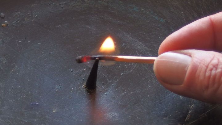 Eine Hand h&auml;lt ein Streichholz, w&auml;hrend es eine kleine Kerze anz&uuml;ndet, um sie sicher im Kerzenst&auml;nder zu platzieren.