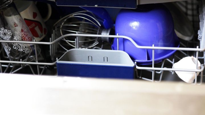 Geschirrsp&uuml;ler mit Geschirr, Becher und Schneebesen in einem Sp&uuml;lmaschinenkorb. Eine Sp&uuml;lmaschine mit offenem Korb.