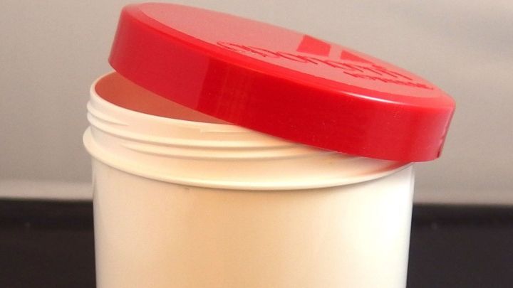 Eine wei&szlig;e Schraubdose mit rotem Deckel steht ge&ouml;ffnet auf einem Tisch, bereit zur Verwendung in einer Apotheke.