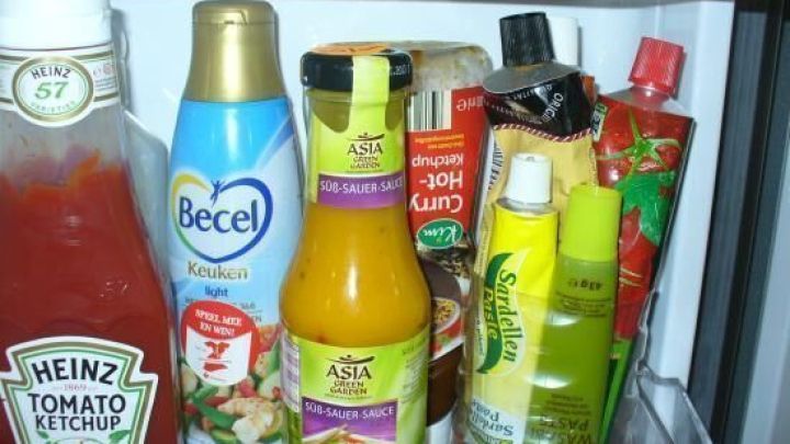 Flaschen und Tuben sind im K&uuml;hlschrank ordentlich eingeordnet, zusammen mit verschiedenen Lebensmitteln in einem frischen Umfeld.