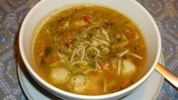 Eine Sch&uuml;ssel Blitz-Gem&uuml;sesuppe mit buntem Gem&uuml;se und feinen Nudeln auf einem dekorativen Tischmuster.