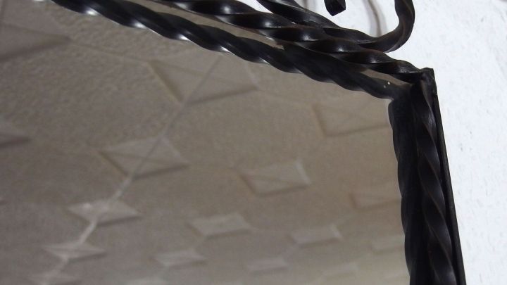 Ein Spiegel mit einem schwarzen, gedrehten Rahmen zeigt seine Oberfl&auml;che, die m&ouml;glicherweise Kratzer enth&auml;lt.