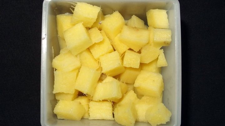 Kleinw&uuml;rfel aus frischem Ingwer liegen in einer wei&szlig;en Sch&uuml;ssel auf einem schwarzen Hintergrund, bereit zur Nutzung.