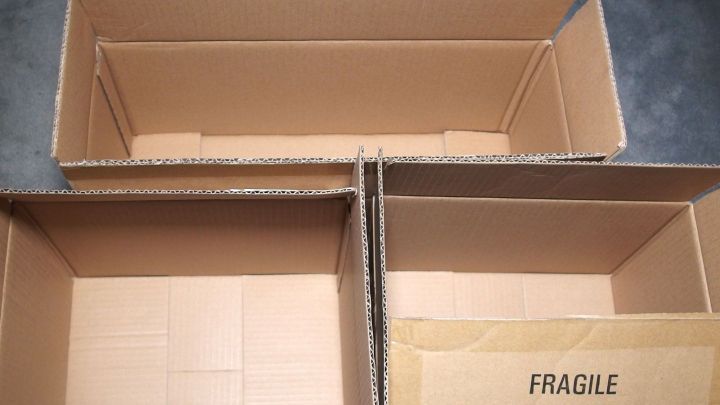 Leere Supermarkt-Kartons liegen in einer ungeordneten Anordnung auf einem grauen Boden, bereit zur weiteren Verwendung.