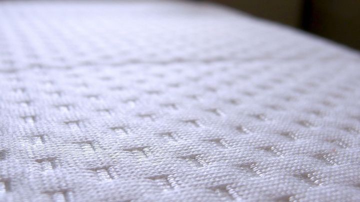 Eine wei&szlig;e Matratze liegt auf einem Bett und zeigt eine strukturierte Oberfl&auml;che, w&auml;hrend sie auf Blutflecken &uuml;berpr&uuml;ft wird.