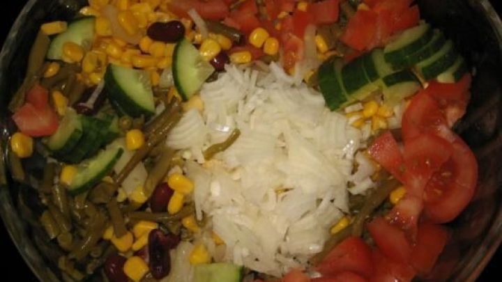 Ein bunter Sommersalat mit Tomaten, Gurken, Mais, Zwiebeln, Bohnen, in einer Glassch&uuml;ssel arrangiert, bereit zum Servieren.