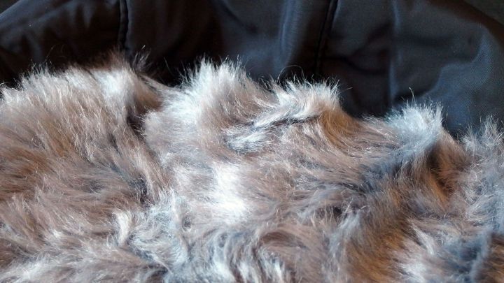 Ein Kleidungsst&uuml;ck mit fell&auml;hnlichem Material liegt auf schwarzem Stoff, bereit zum Waschen.