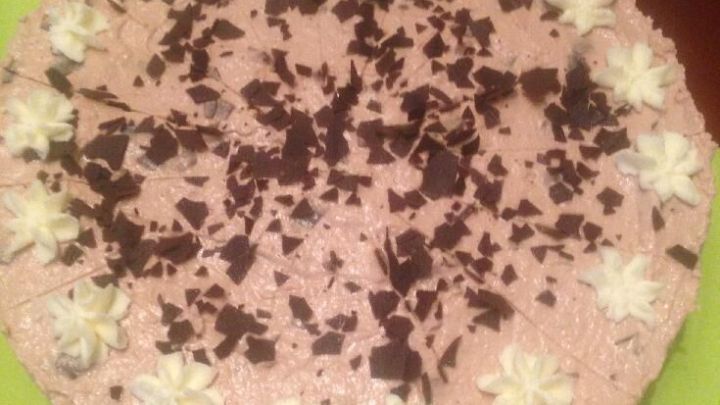 Eine verf&uuml;hrerische Cappuccino-Philadelphia-Torte ruht auf einem gr&uuml;nen Tisch, umgeben von eleganten Gl&auml;sern.