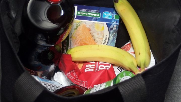 Eine Einkaufstasche enth&auml;lt Flasche, Snacks und Bananen, die f&uuml;r den n&auml;chsten Einkauf ausgelegt sind.