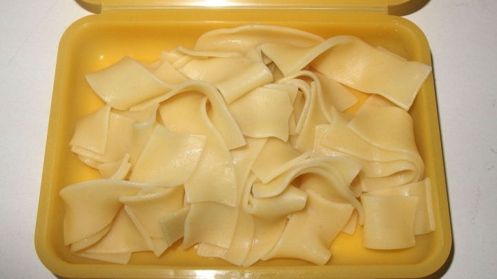 In einem gelben Beh&auml;lter liegen frisch gekochte, aromatische Nudeln, die sanft &uuml;bereinander geschichtet sind.