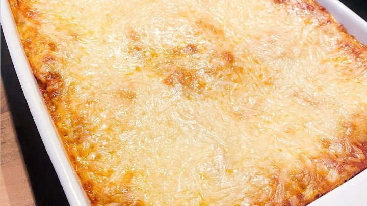 Eine goldbraun gebr&auml;unte K&auml;sekruste auf einem Auflauf, frisch aus dem Ofen, auf einer schwarzen Kochplatte platziert.