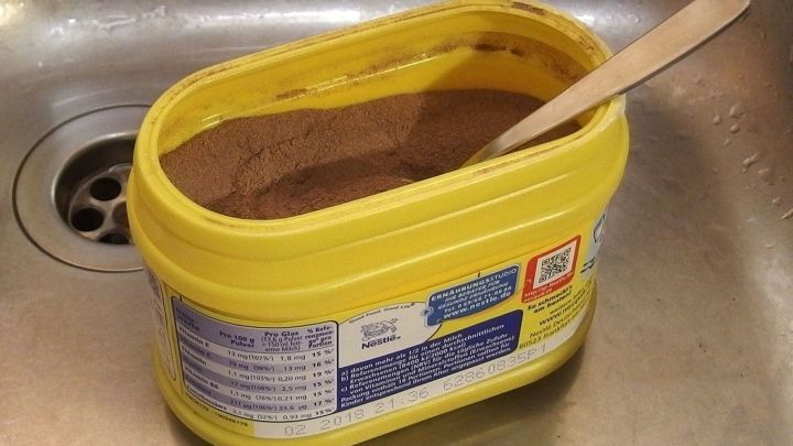 Eine gelbe Dose mit Pulver steht in der K&uuml;che neben einem Waschbecken, einem Holzl&ouml;ffel zugeh&ouml;rig, bereit zum Gebrauch.