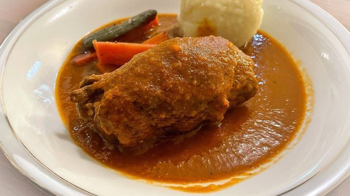 Ein saftiges Pferderoulade liegt in einer w&uuml;rzigen So&szlig;e, umgeben von Gem&uuml;se und einer Portion Beilage auf einem Teller.