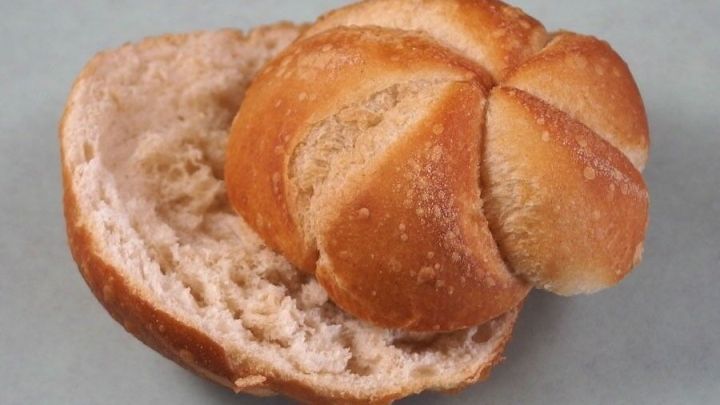 Eine Semmel liegt offen auf einer Fl&auml;che, die weiche Innenseite zeigt, bereit zur Verwendung oder zum Verzehr.