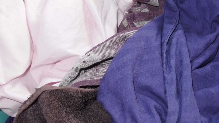 Bunte Textilien liegen ungeordnet und knittrig aufeinander, wie frisch aus einem Kondenstrockner entnommen.